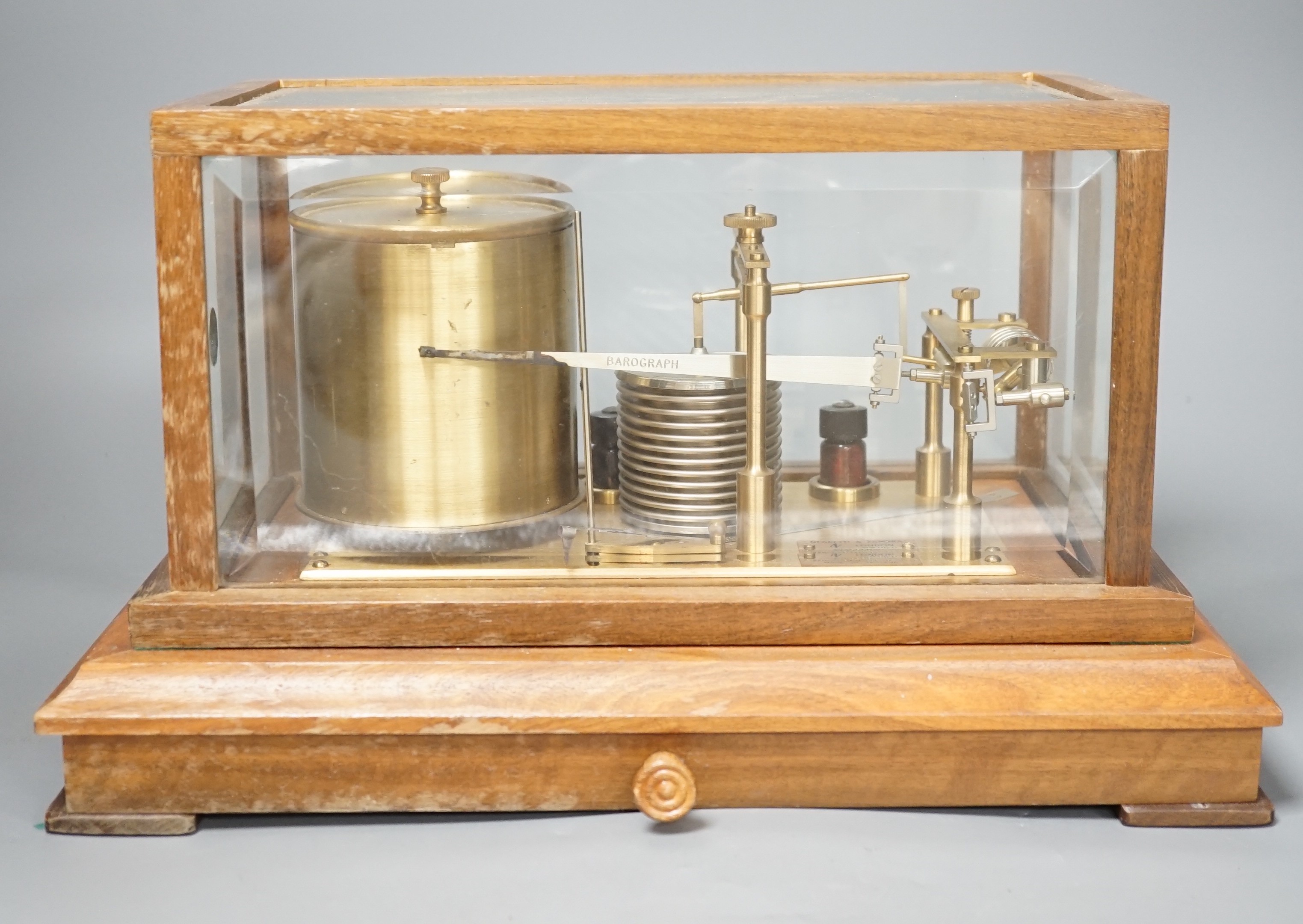 A Negretti & Zambra teak barograph with spare graph paper in case draw. 36cm wide.